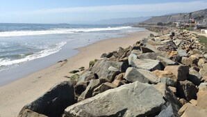 A rocky beach with a clear view of the ocean and distant mountains.