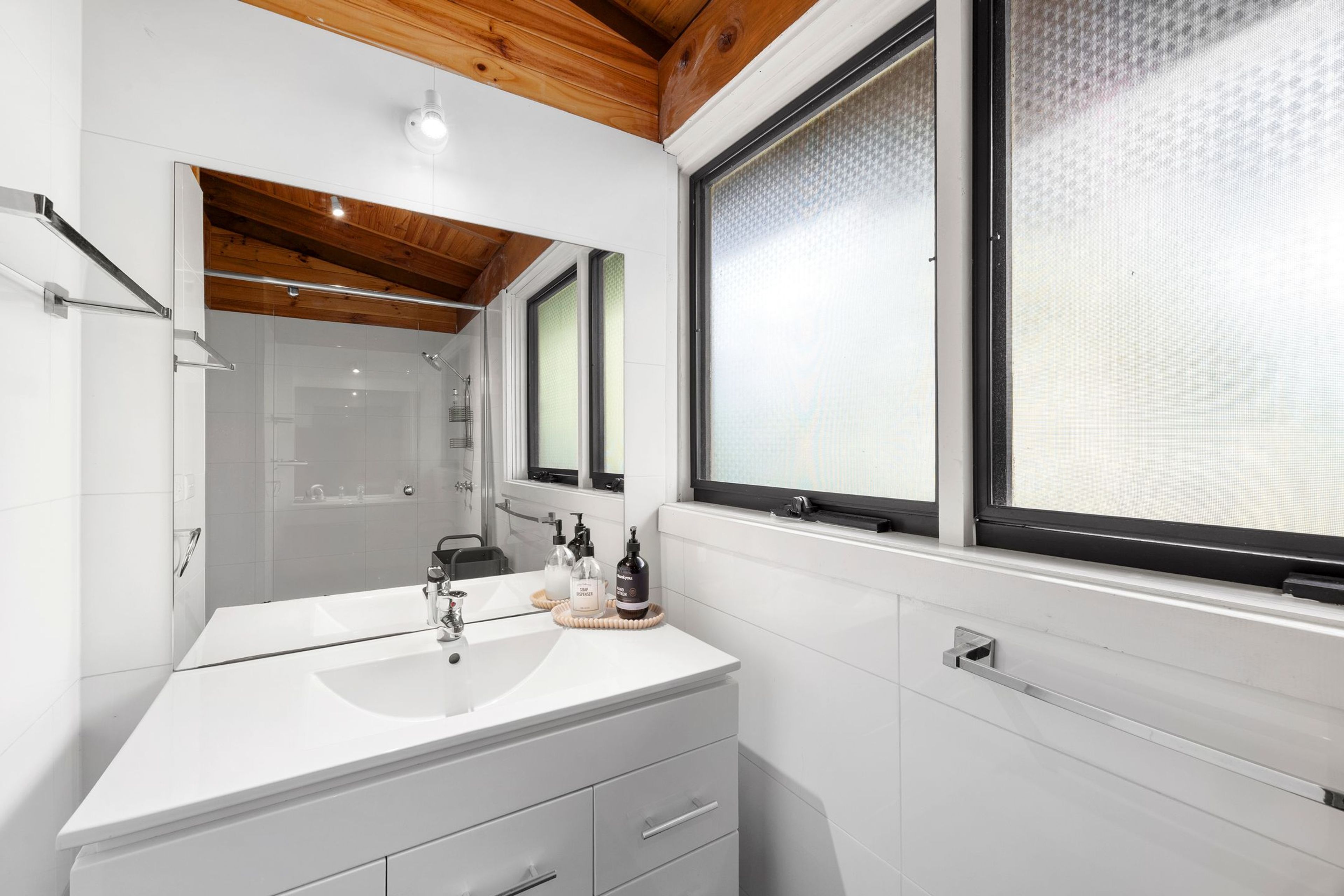 Un bagno moderno con un mobile lavabo bianco, cabina doccia in vetro e un'ampia finestra vista panoramica.