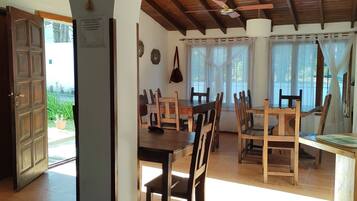 An open-plan dining area with wooden furniture and a high ceiling.