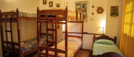A room with three wooden bunk beds, a small table, and a wall with various decorations.