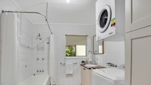 Ein modernes Badezimmer mit Badewanne, Dusche, Toilette und einer integrierten Waschmaschine.