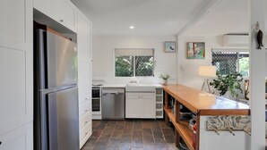 Eine moderne Küche mit weißen Schränken, einem Edelstahlkühlschrank, einem Geschirrspüler und einer Holz Arbeitsplatte.