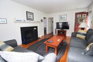 A living room with a fireplace, a television, and a sofa. - 4BR Cape Style Near Saints Landing and Paines Creek (2086) (Brewster)