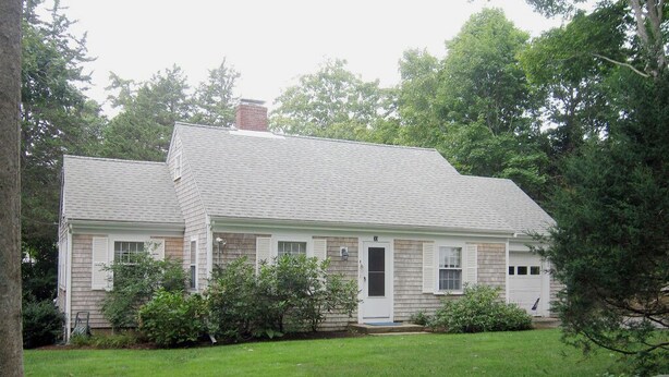 A two-story house with a front porch, a garage, and a well-maintained lawn. - 4BR Cape Style Near Saints Landing and Paines Creek (2086) (Brewster)