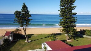 Blick auf einen Strand mit einem Haus, einer Holzterrasse und einem Gebäude mit rotem Dach.
