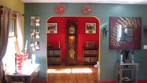 Ein Zimmer mit Holzboden, einer großen Standuhr und Bücherregalen voller Bücher.