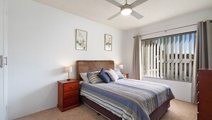 A bedroom with a bed, nightstands, a ceiling fan, and a window with blinds. - Sunrise Court 3 - Bilinga/ North Kirra Beachfront (Bilinga)