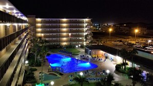 Un hotel con piscina, varias plantas y zona de estacionamiento.