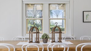 A dining area with a wooden table and white chairs, two wooden lanterns with hanging question marks, and a potted plant on the table. - Spacious Sorrento Retreat (Sorrento)