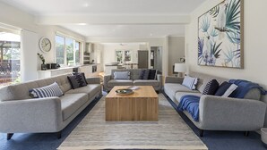 A spacious living room with two grey sofas, a wooden coffee table, and a large abstract painting on the wall. - Spacious Sorrento Retreat (Sorrento)