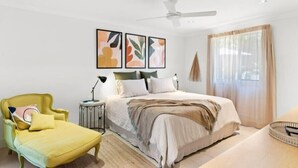 Une chambre à coucher comprenant un lit, une chaise, une table de chevet et une œuvre d’art abstraite accrochée au mur.