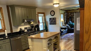 A spacious kitchen with wooden cabinets, a central island, and a dining area with a patterned rug and a metal chair.