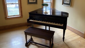 A piano room with a piano, a bench, and three framed pictures on the walls.