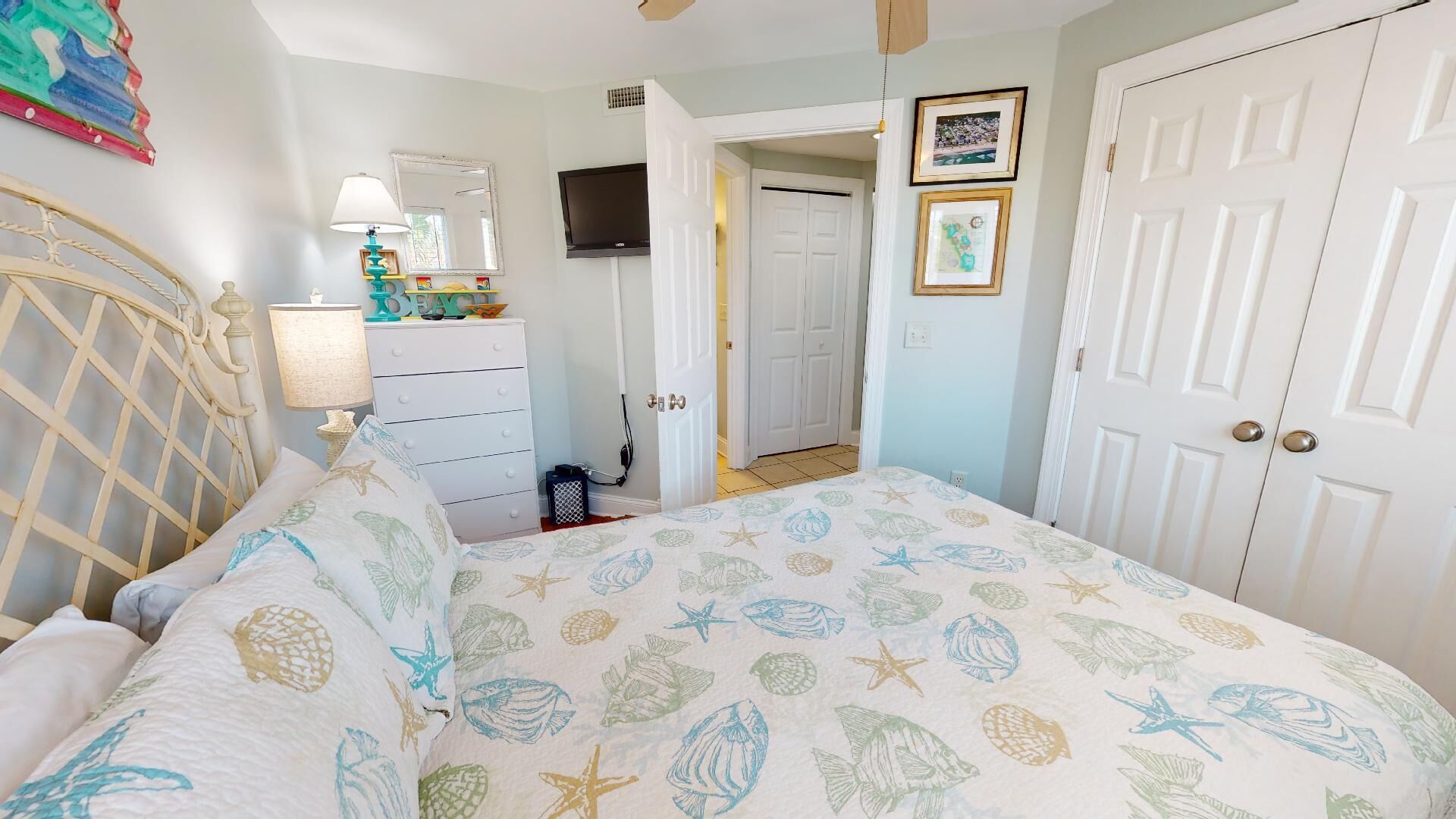 A bedroom with a bed, dresser, and a door leading to another room.