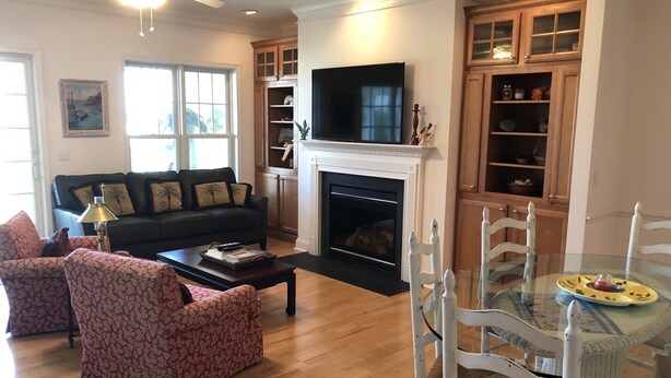A living room with a fireplace, a television, and a dining area with a glass table.