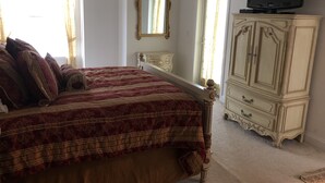 A bedroom with a large bed, a television on a cabinet, and a mirror on the wall.