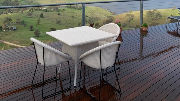 A wooden deck with a table and chairs, overlooking a valley with a rainbow. - Amazing Views Pet Friendly Bed and Breakfast (Good Hope)