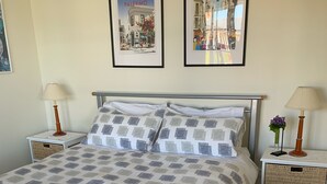 A neatly made bed with a checkered bedspread, two pillows, and two folded towels. There are two framed pictures on the wall above the bed. - Amazing Views Pet Friendly Bed and Breakfast (Good Hope)