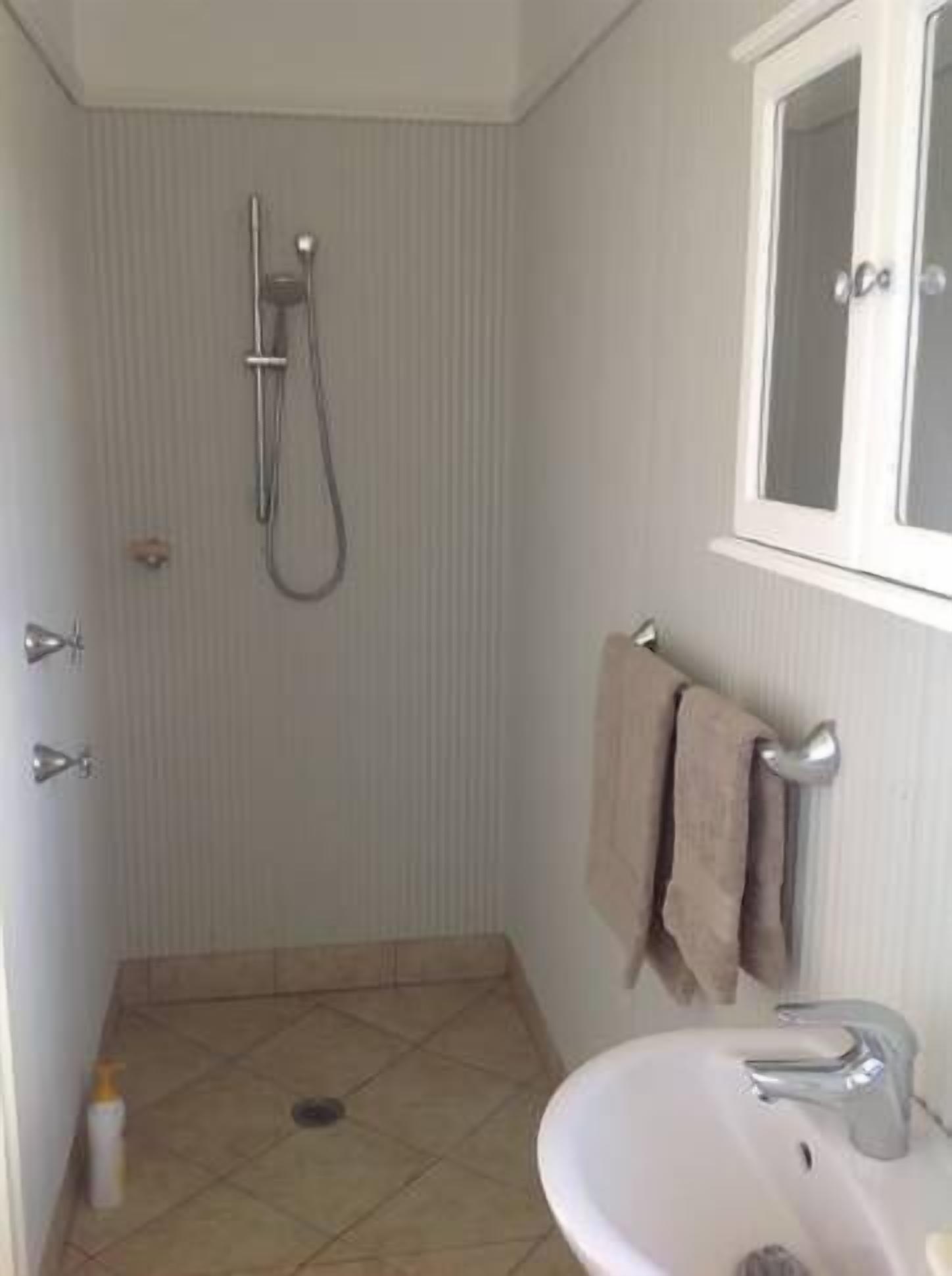 Un bagno piccolo con doccia, lavandino e finestra.
