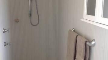 Un bagno piccolo con doccia, lavandino e finestra.
