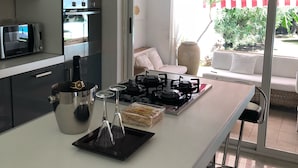A modern kitchen with a central island, built-in appliances, and a view to an outdoor seating area. - Villa Ines, sul mare con piscina (CAPOTERRA)