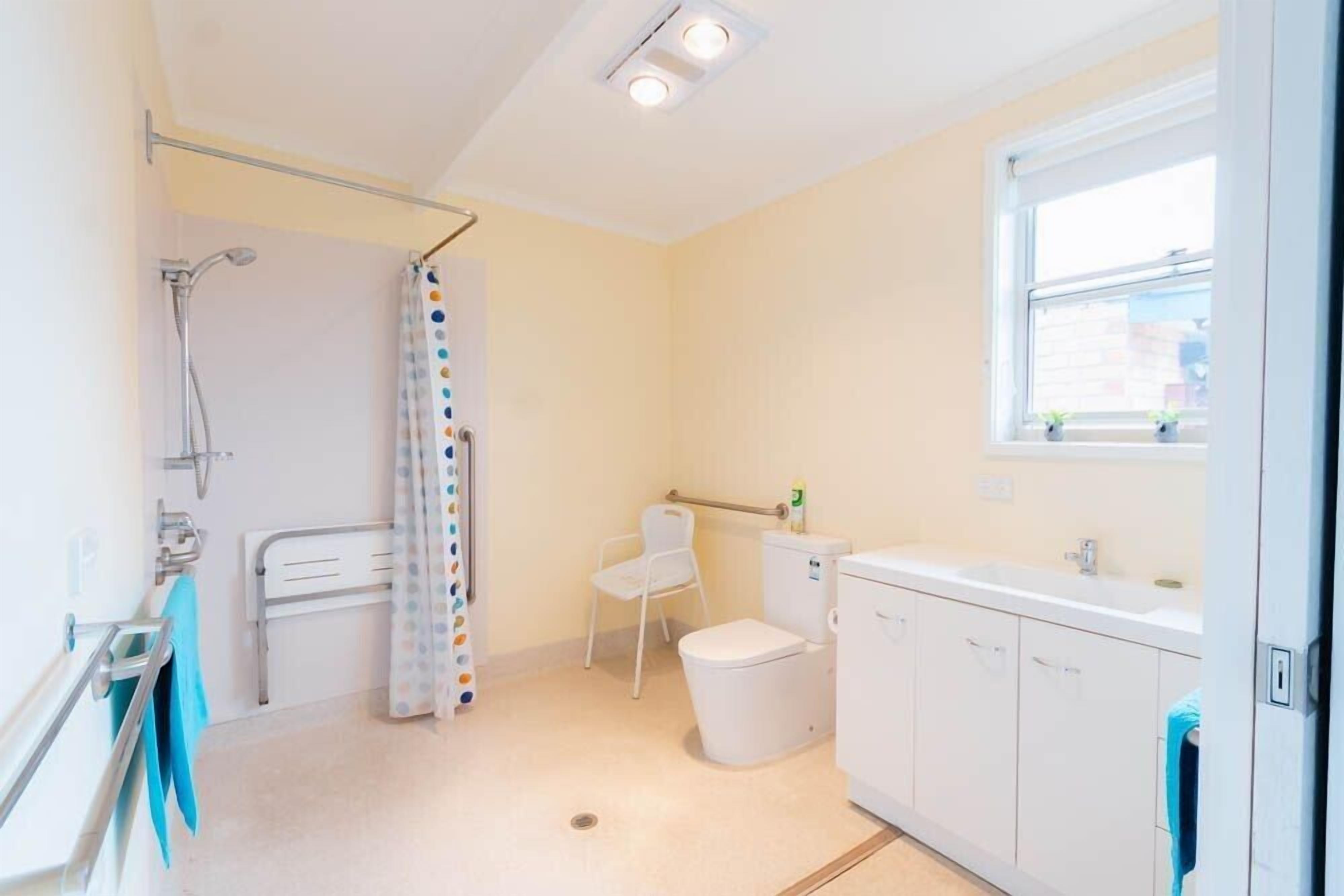Une petite salle de bain propre, équipée d’une douche, de toilettes et d’un lavabo.