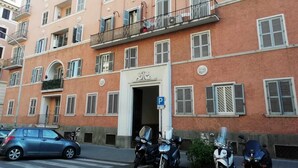 Un edificio de varios pisos con una entrada central, balcones y motocicletas estacionadas.
