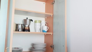 Cozinha com prateleiras abertas, contendo utensílios de cozinha e pratos.