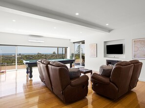 A modern living room with a pool table, leather recliners, a flat-screen TV, and a balcony with a view. - Top Class Rye Getaway with Pool (RYE)