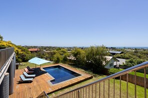 A residential backyard with a swimming pool, deck chairs, and a view of the neighborhood. - Top Class Rye Getaway with Pool (RYE)