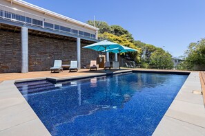 A swimming pool with a stone wall and a wooden deck.