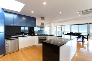 A modern kitchen with a central island, stainless steel appliances, and a view to the outdoors. - Top Class Rye Getaway with Pool (RYE)
