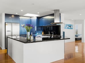 Una cucina moderna con isola centrale, elettrodomestici in acciaio inossidabile e una parete di accento blu.