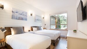 Un dormitorio moderno con dos camas, un televisor y obras de arte en la pared.