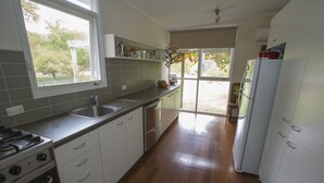 A kitchen with a gas stove, sink, and white cabinets. - Riverside House on the beautiful Howqua River (Howqua)