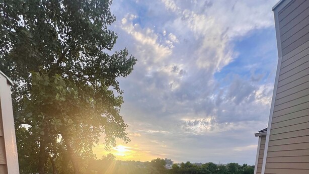 Un balcone con due sedie e un tavolino, con vista su un lago al tramonto.