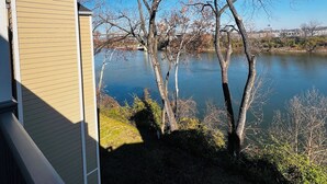 Vista di un lago con alberi spogli e un edificio dalla facciata beige.