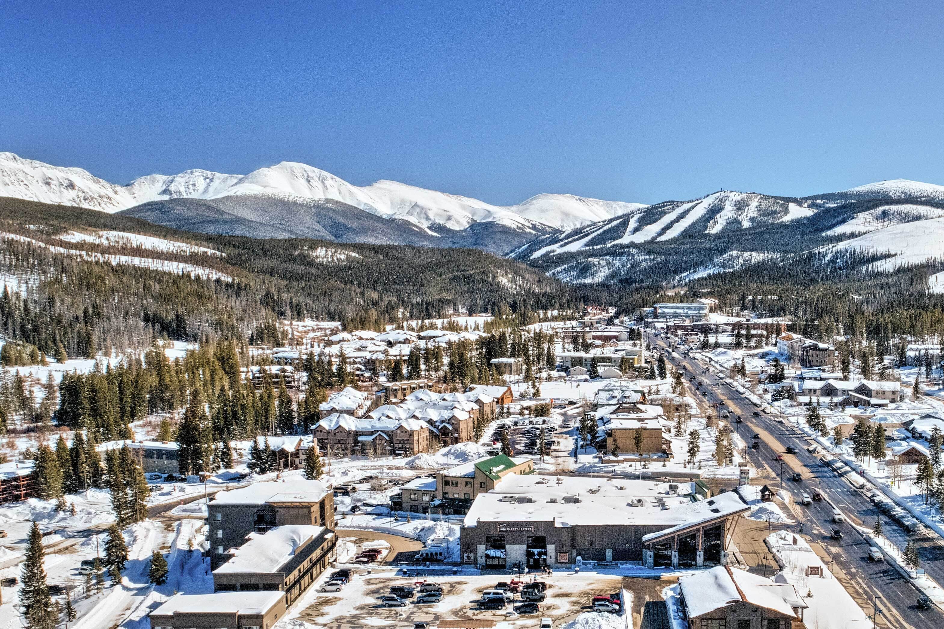 A town with buildings, roads, and snow-covered mountains in the background.