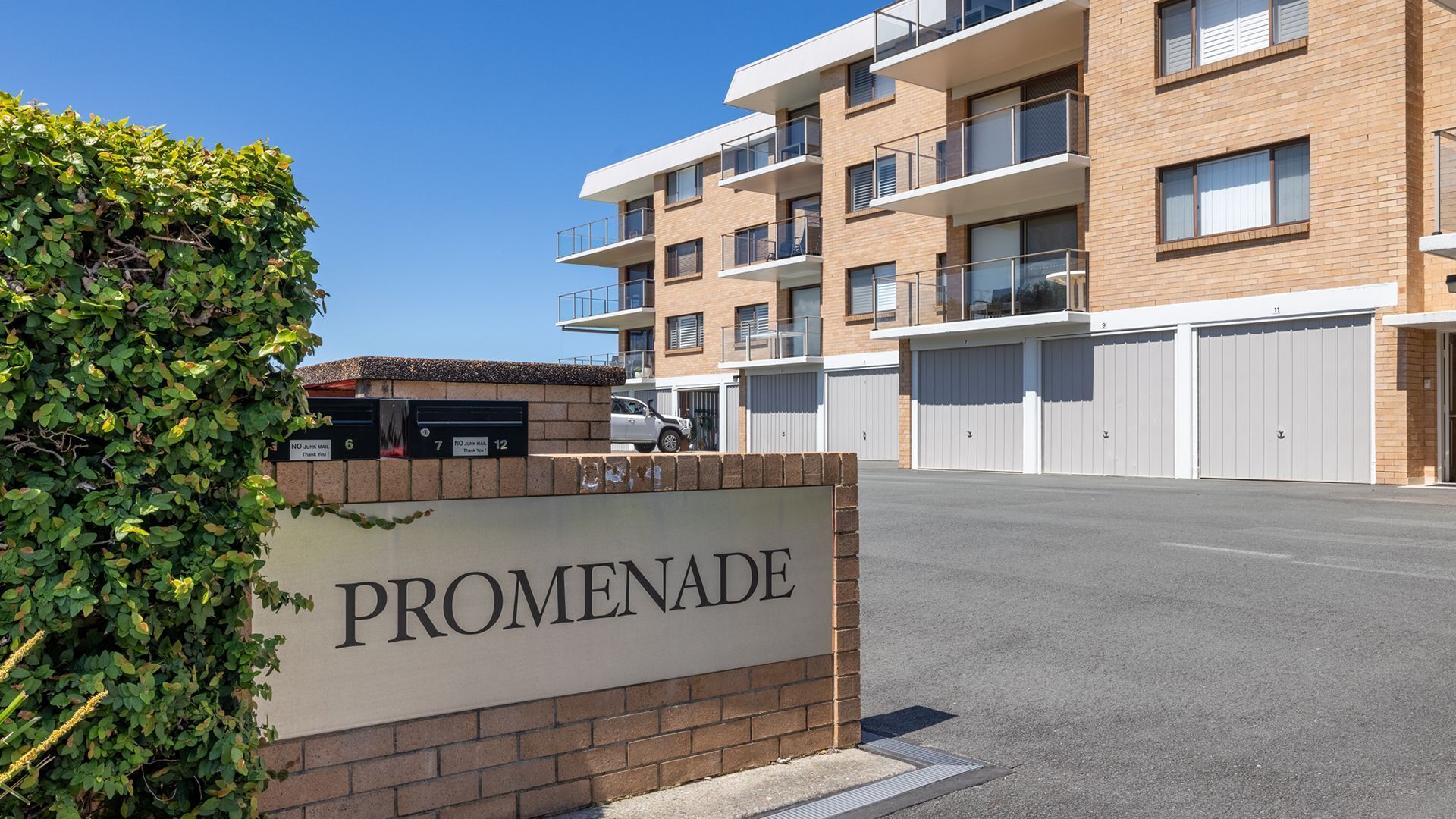 Un immeuble à plusieurs étages, avec une enseigne indiquant « PROMENADE » et un espace de stationnement devant.