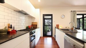 Una cocina moderna con armarios blancos, encimera negra y suelo de madera.