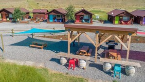 Un camping con cabañas de madera, mesas de picnic y parrillas.
