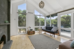 A spacious living room with a fireplace, large windows, and a view of the outdoors.