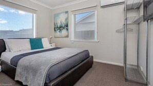 Une chambre à coucher avec un lit, une fenêtre, un tableau et une étagère en métal.