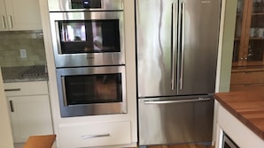 Una cocina con electrodomésticos de acero inoxidable, incluyendo un horno doble y un refrigerador.