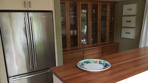 Una cocina con electrodomésticos de acero inoxidable, armarios de madera y encimera de madera.
