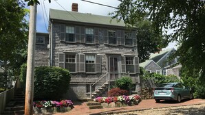 A two-story house with a stone facade, a brick pathway, and a stone driveway. - The Folger House on historic Academy Hill, Nantucket (Nantucket)