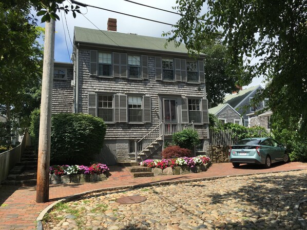 A two-story house with a stone facade, a brick pathway, and a stone driveway.