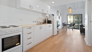A modern kitchen with white cabinets, a built-in oven, and a dining area with a table and chairs.
