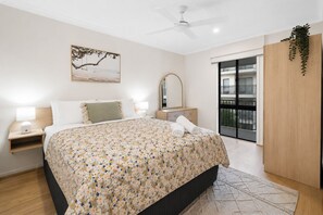 A bedroom with a bed, bedside tables, a ceiling fan, a large window, and a balcony. - Scarborough Beach Escape NEW (Scarborough)