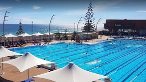 A swimming pool with multiple lanes, sun loungers, and umbrellas.